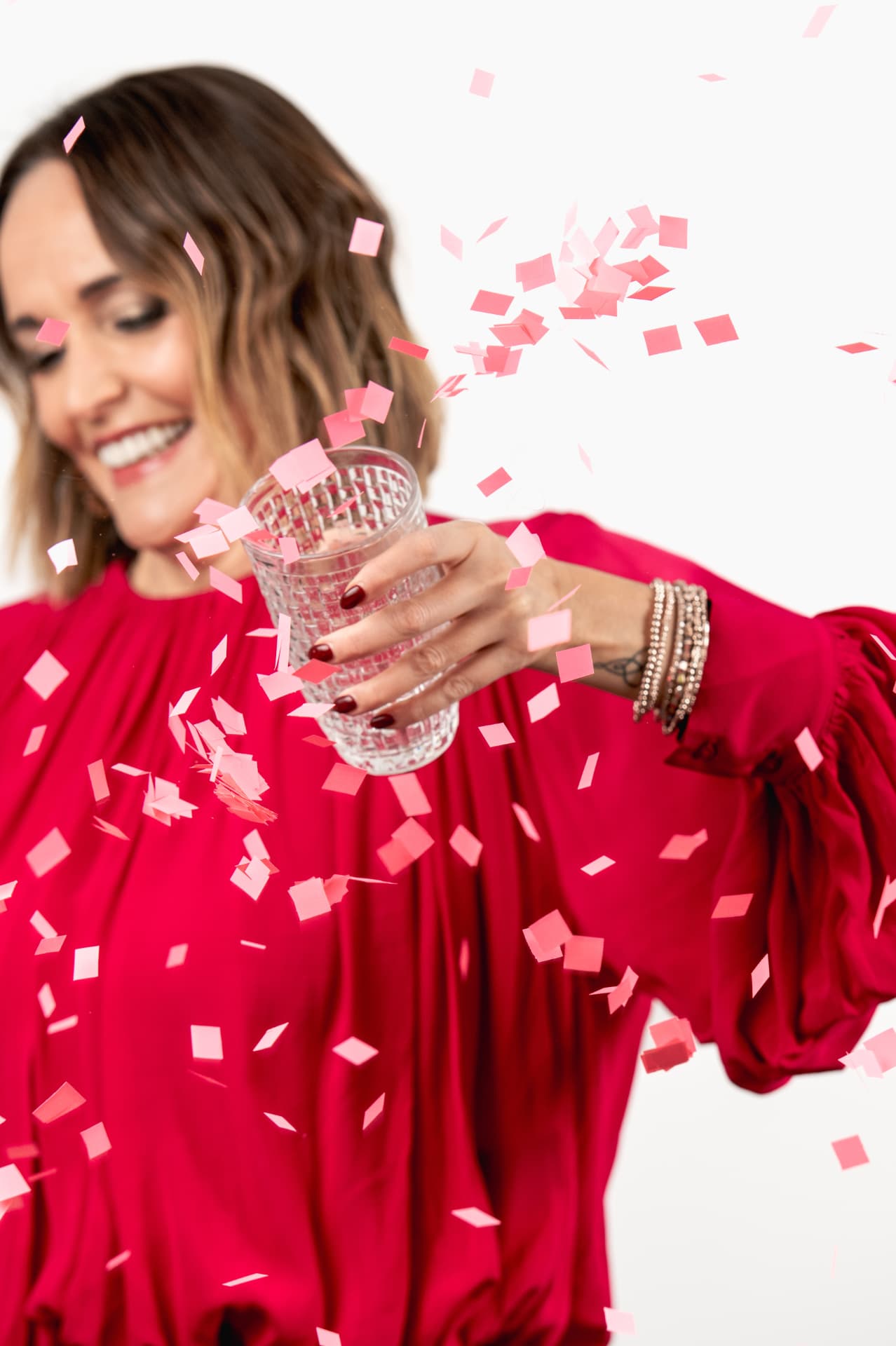 Claire Marshall raising a glass surrounded by pink confetti